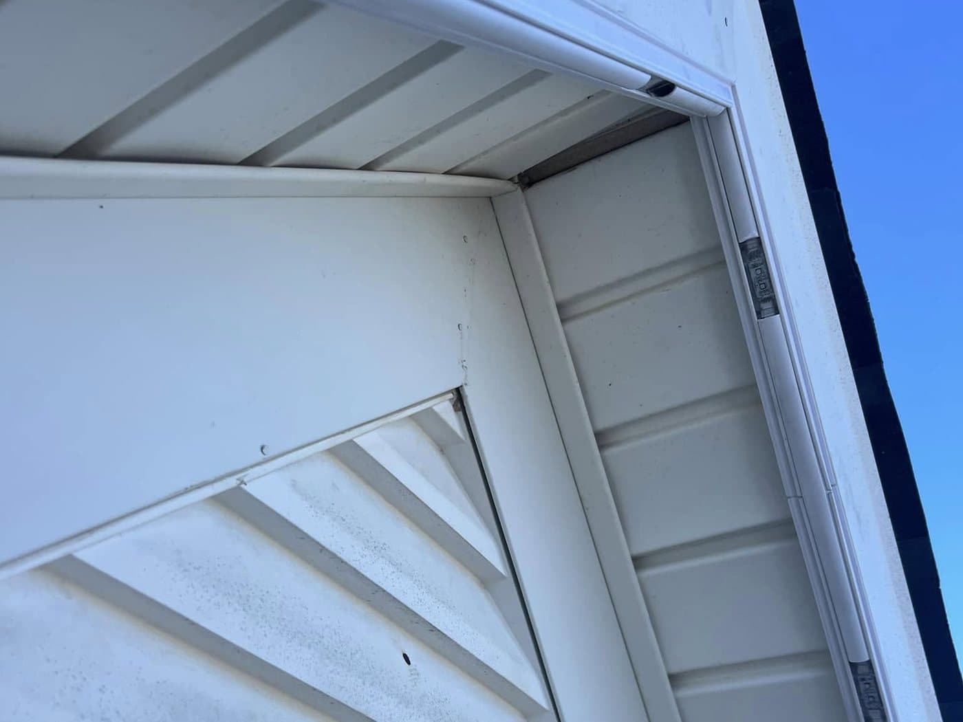 Daytime close-up of the white permanent lighting track tucked under the soffit and along the fascia, matched to the trim